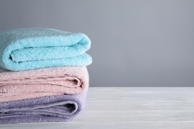 Photo of Fresh towels on wooden table, space for text