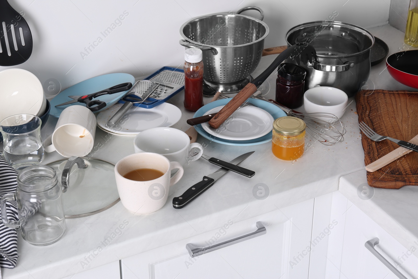 Photo of Many dirty utensils, cookware and dishware on countertop in messy kitchen