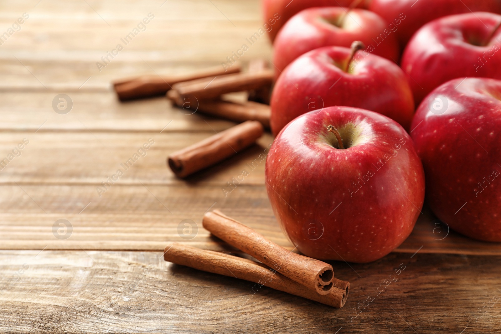 Photo of Fresh apples and cinnamon sticks on wooden table