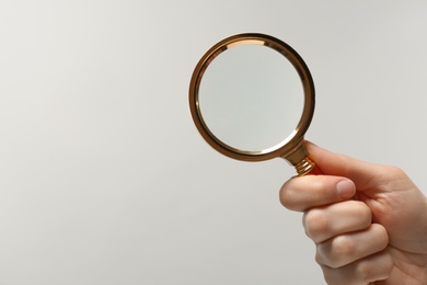 Photo of Woman holding magnifying glass on white background, closeup. Space for text