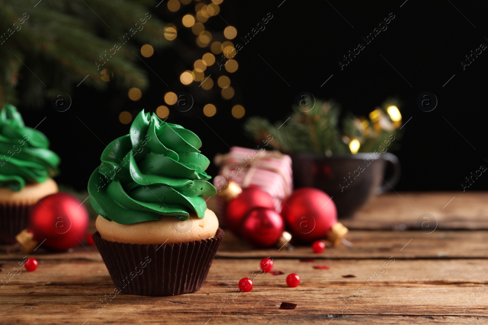 Photo of Delicious cupcake with green cream and Christmas decor on wooden table