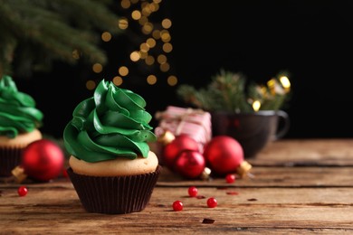 Photo of Delicious cupcake with green cream and Christmas decor on wooden table