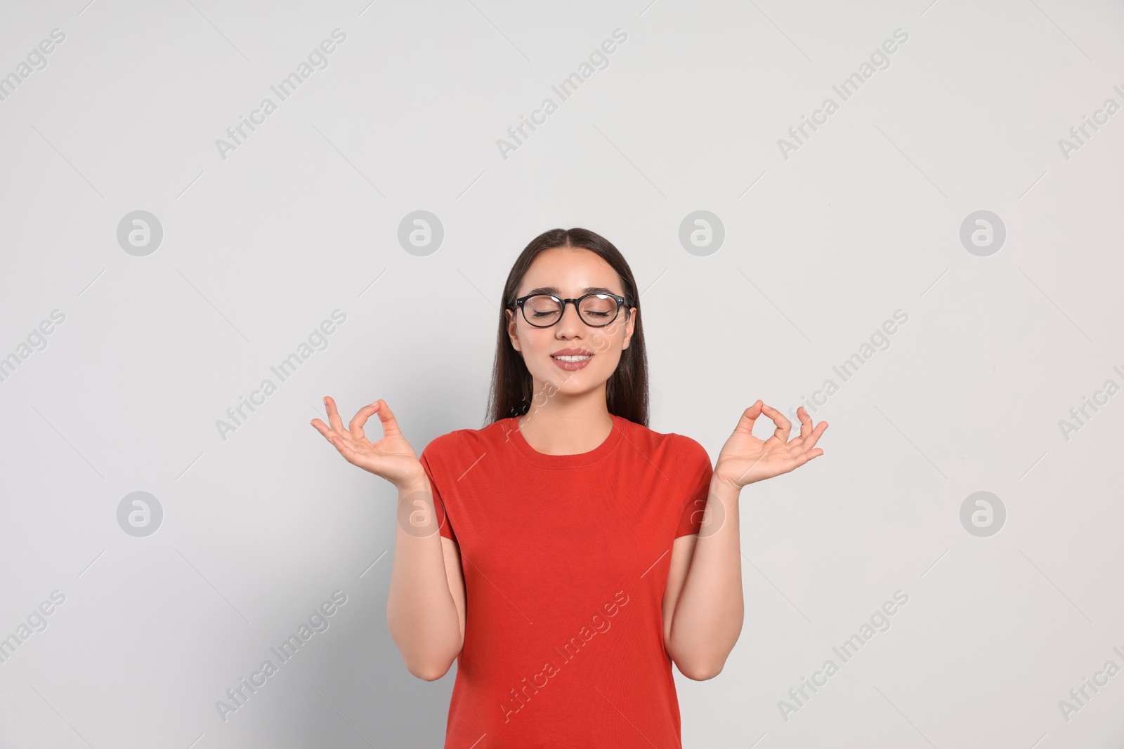 Photo of Find zen. Beautiful young woman meditating on white background