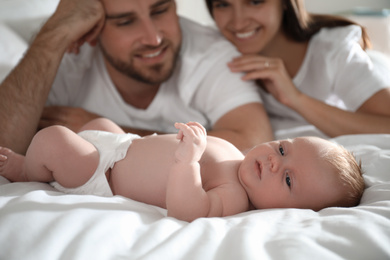 Photo of Happy couple with their newborn baby on bed, closeup