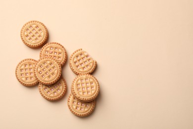 Tasty sandwich cookies with cream on beige background, flat lay. Space for text