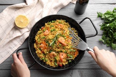 Woman taking tasty fried rice at grey wooden table, top view