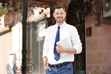 Portrait of young businessman with tablet outdoors