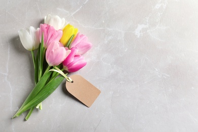 Photo of Beautiful tulips and blank label on marble background, top view with space for text. International Women's Day