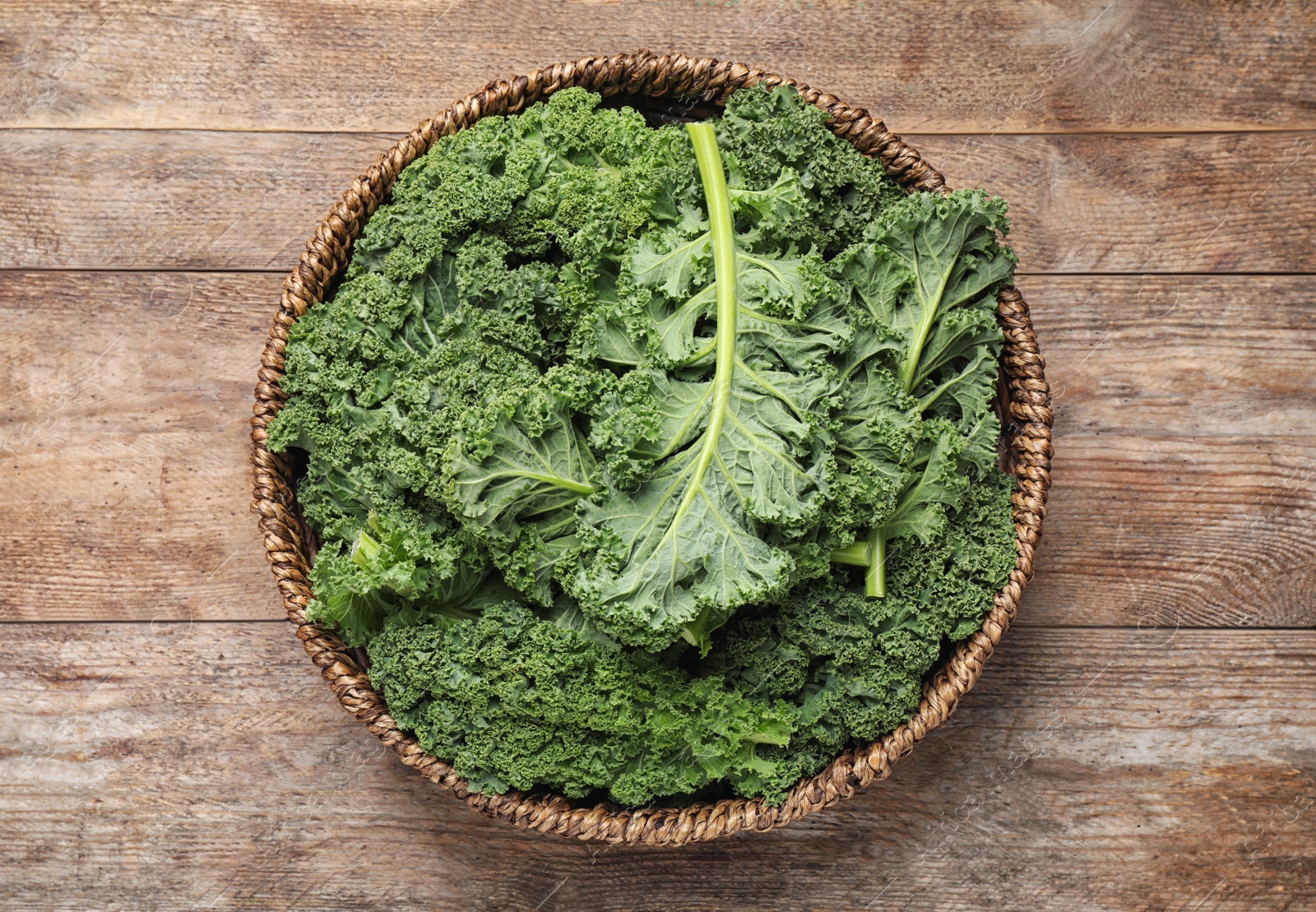 Photo of Fresh kale leaves on wooden table, top view