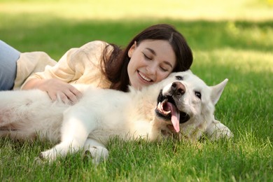 Photo of Teenage girl lying with her white Swiss Shepherd dog on green grass in park