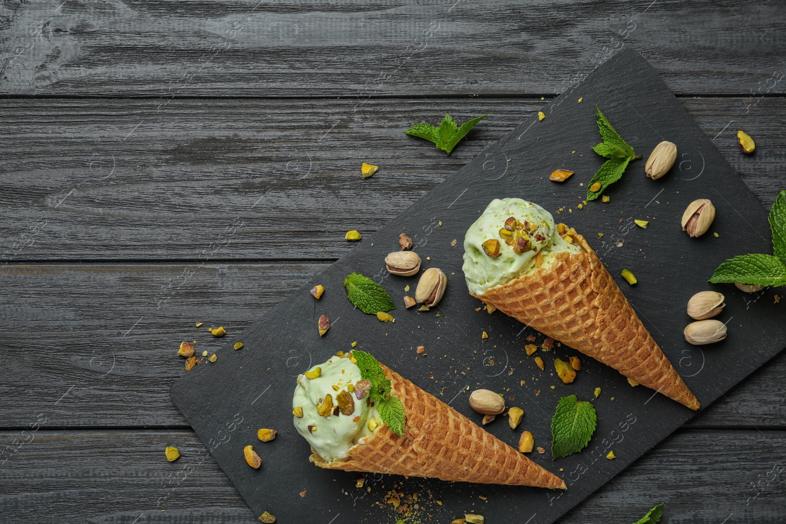 Photo of Delicious green ice cream served on wooden table, flat lay. Space for text