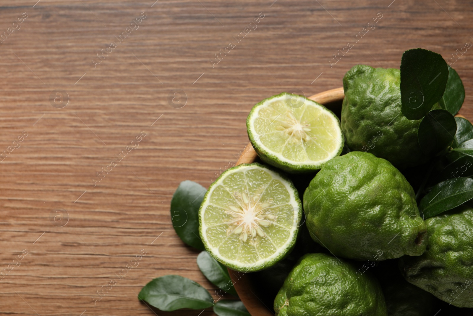 Photo of Fresh ripe bergamot fruits with green leaves on wooden table, top view. Space for text