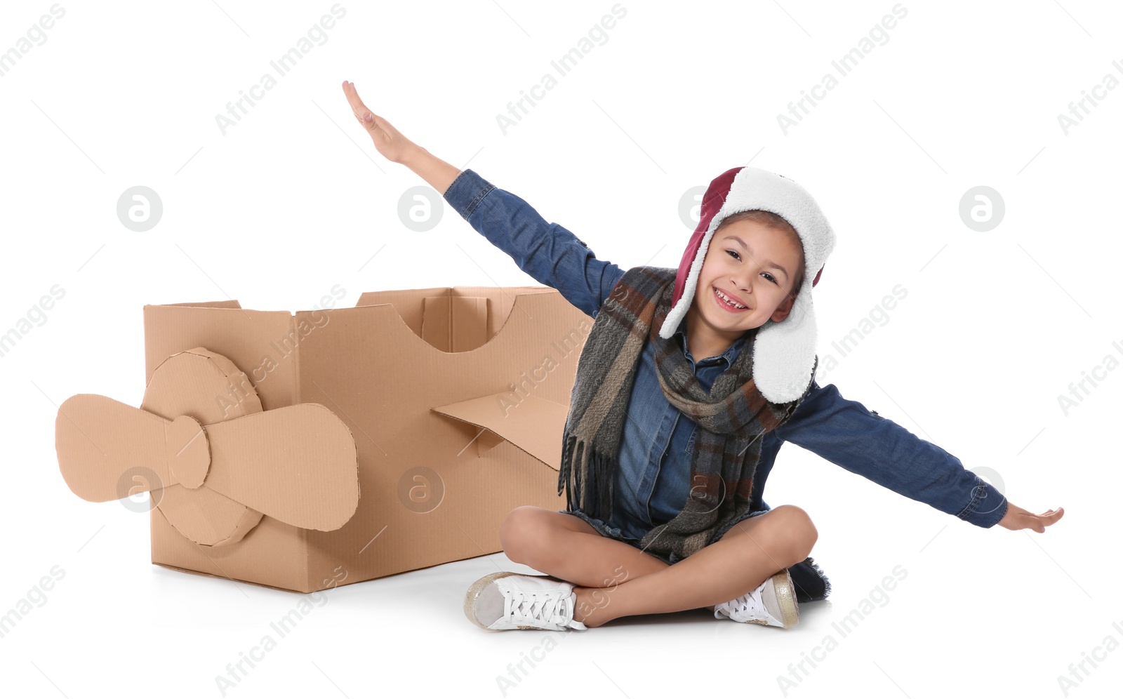 Photo of Cute little girl playing with cardboard airplane on white background