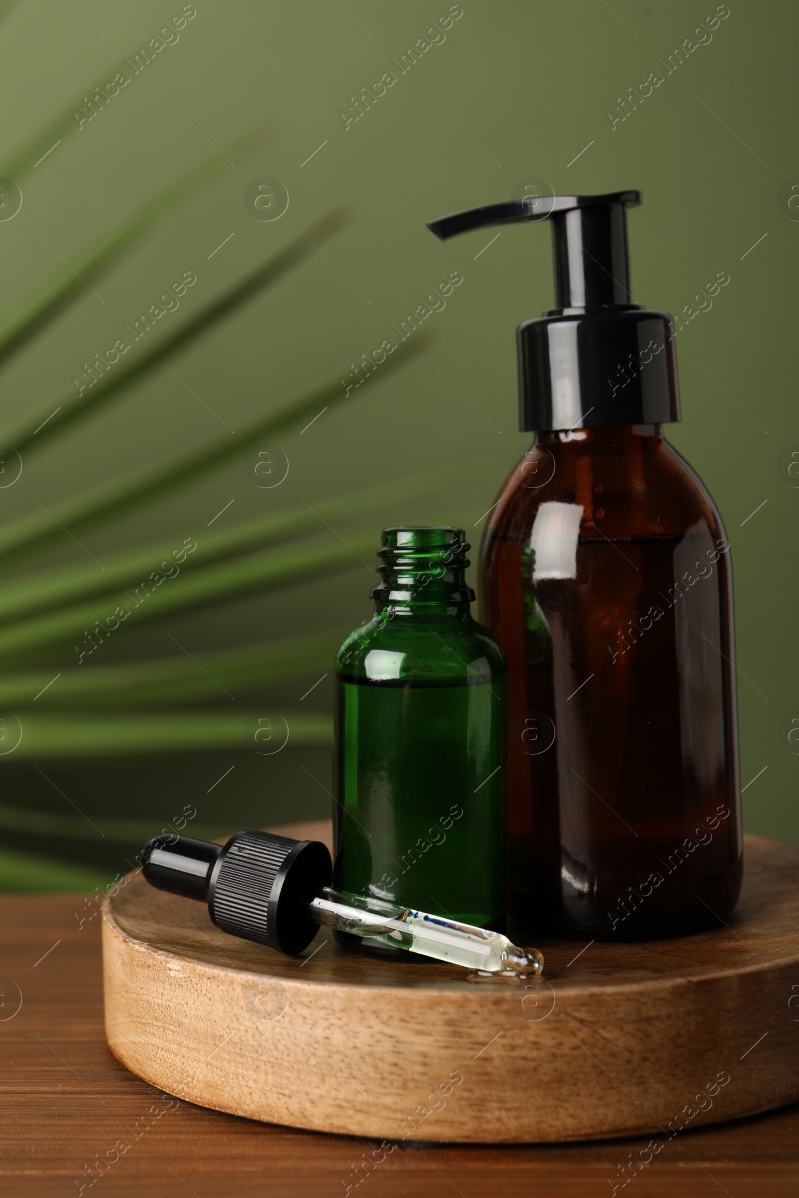 Photo of Bottles of hydrophilic oil on wooden table against green background