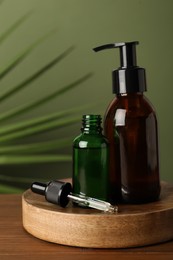 Photo of Bottles of hydrophilic oil on wooden table against green background