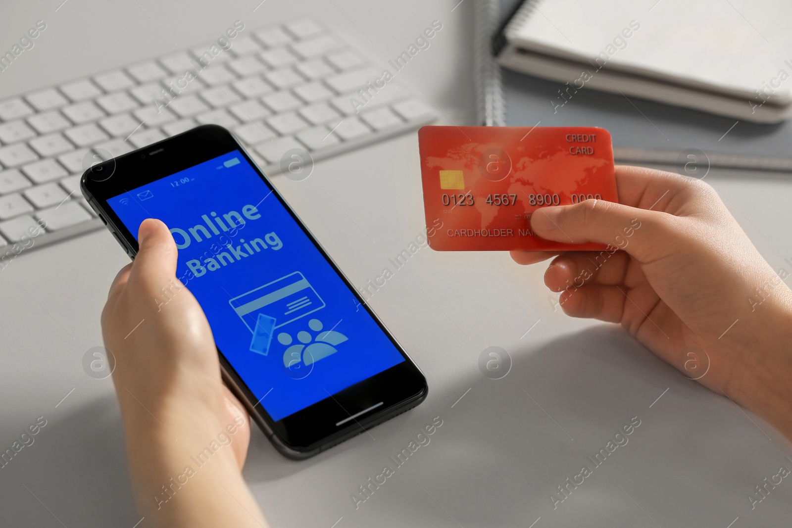 Photo of Woman using online banking app on smartphone and credit card at white office table, closeup