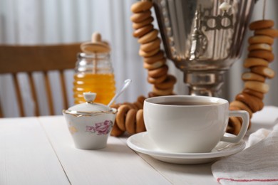 Photo of Composition with delicious ring shaped Sushki (dry bagels) and tea on white wooden table indoors, space for text