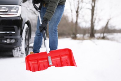 Photo of Man removing snow with shovel near car outdoors on winter day, closeup