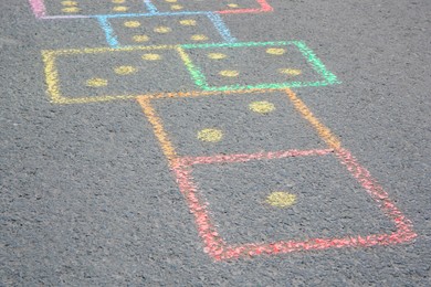 Hopscotch drawn with colorful chalk on asphalt outdoors, closeup