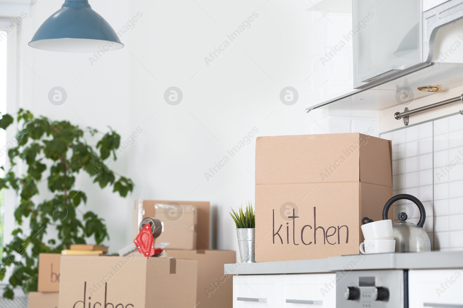 Photo of Moving boxes and household stuff in kitchen. Space for text