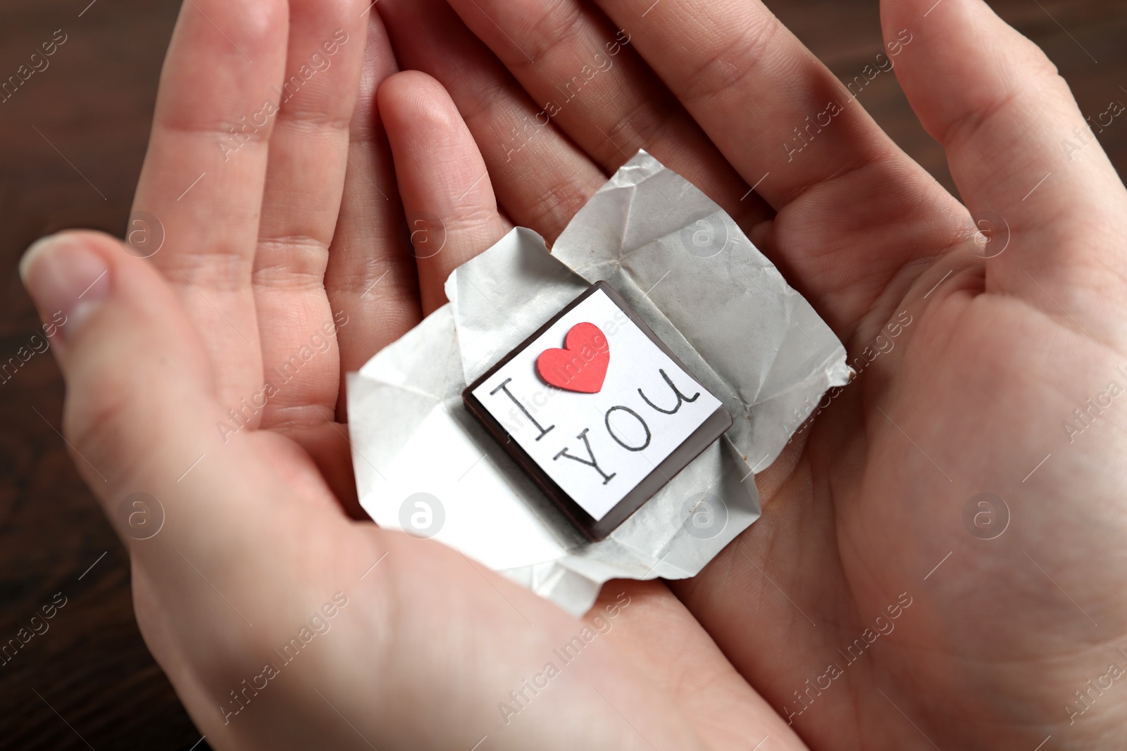 Photo of Woman holding chocolate candy with message I Love You, closeup