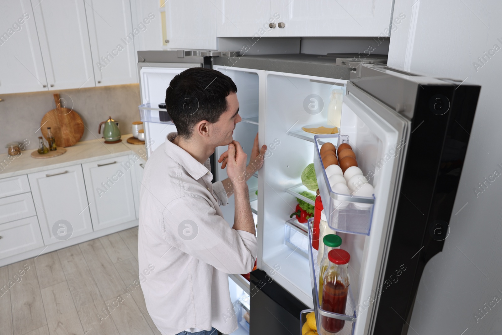 Photo of Thoughtful man near refrigerator in kitchen at home