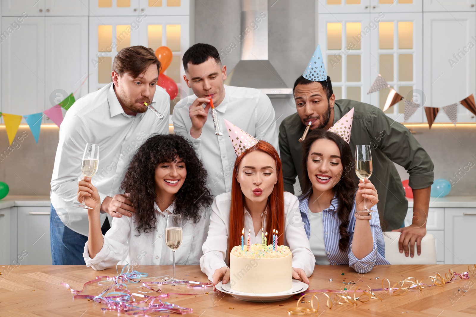 Photo of Happy friends with tasty cake celebrating birthday in kitchen