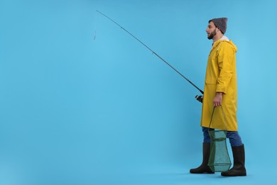 Fisherman with rod and fishing net on light blue background, space for text