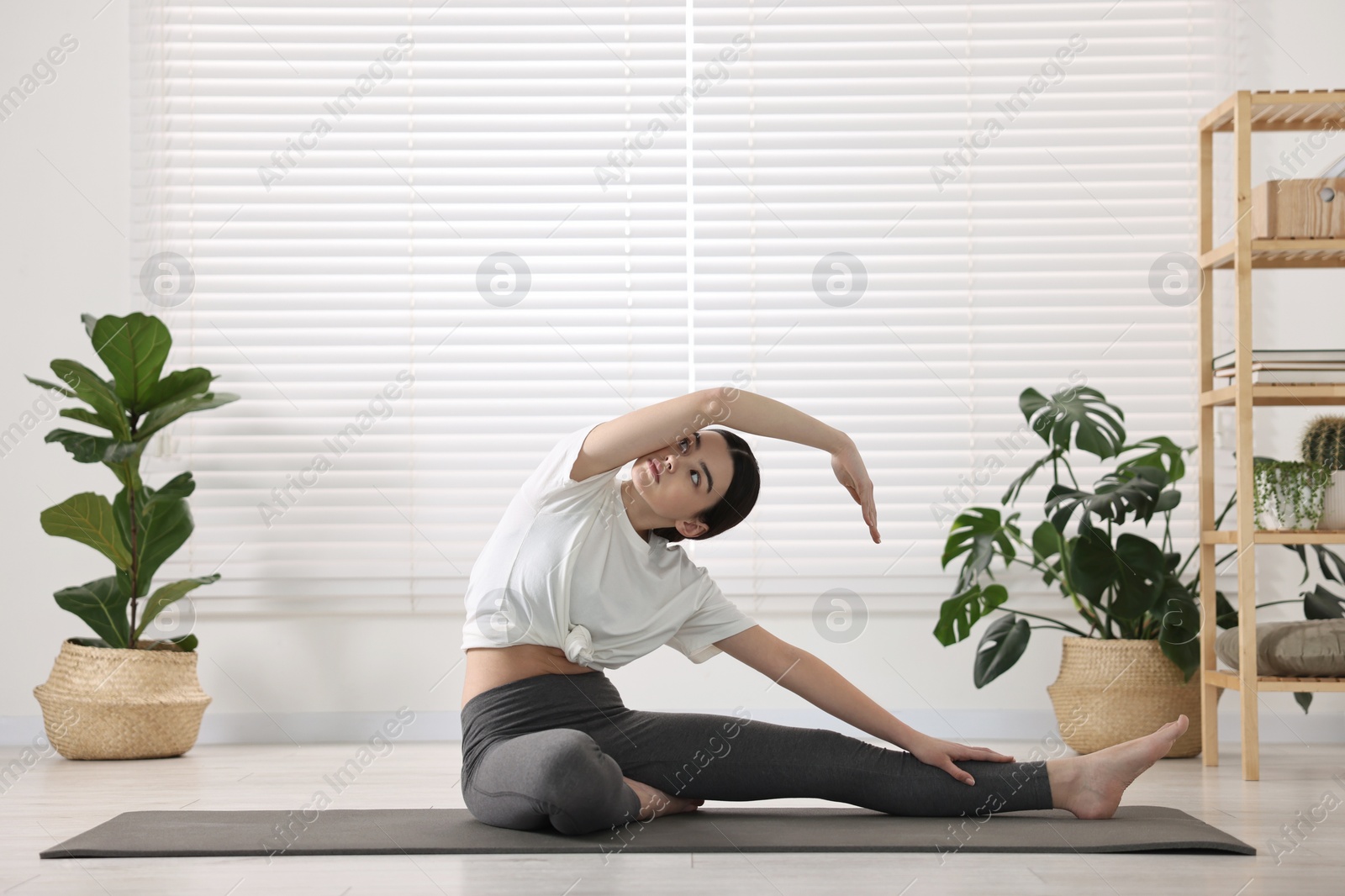 Photo of Girl practicing revolved head to knee asana on mat in yoga studio. Parivrtta janu sirsasana pose