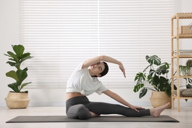 Photo of Girl practicing revolved head to knee asana on mat in yoga studio. Parivrtta janu sirsasana pose