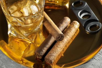 Photo of Tray with whiskey, cigars and cutter on grey table, closeup