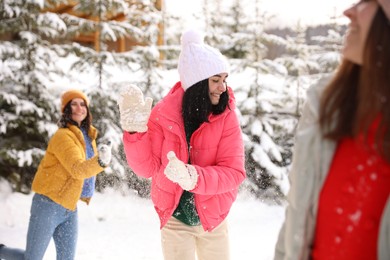 Group of friends playing snowballs outdoors. Winter vacation