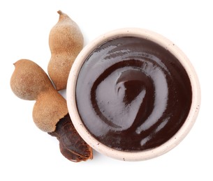 Photo of Bowl of tamarind sauce and fresh pods isolated on white, top view