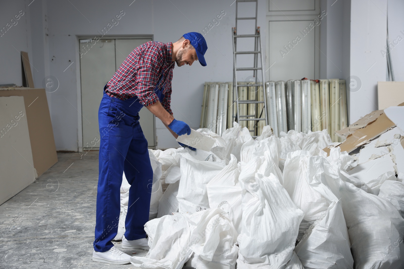 Photo of Construction worker with used building materials in room prepared for renovation