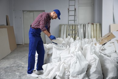 Construction worker with used building materials in room prepared for renovation