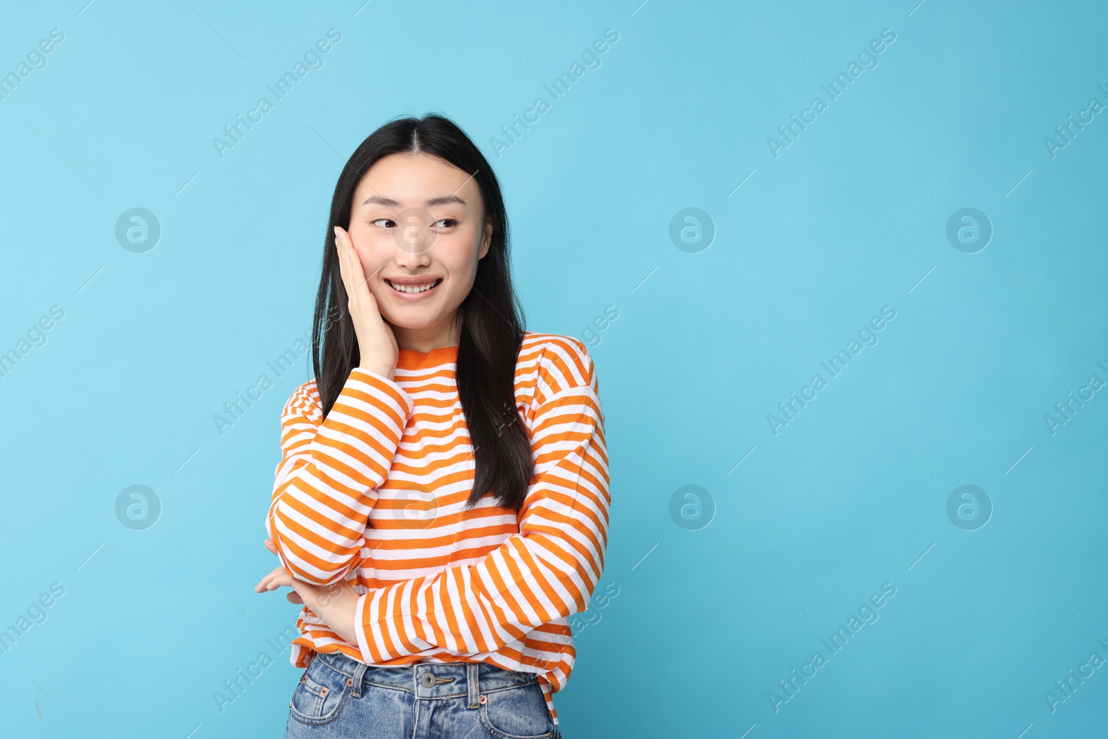 Photo of Portrait of happy woman on light blue background. Space for text