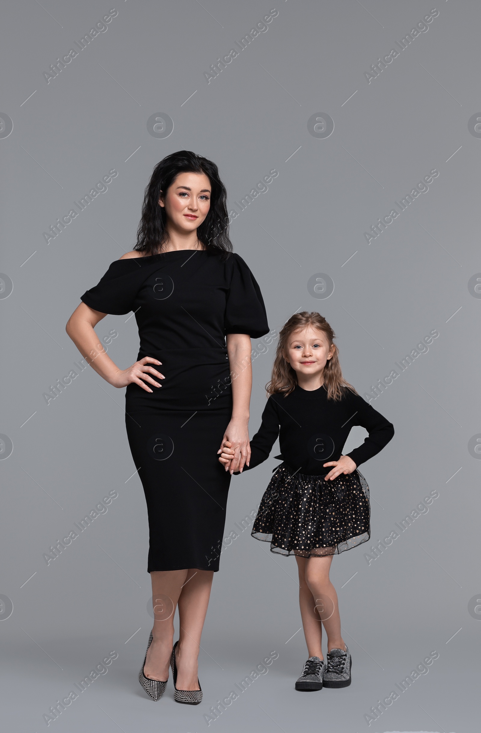 Photo of Beautiful mother with little daughter on grey background