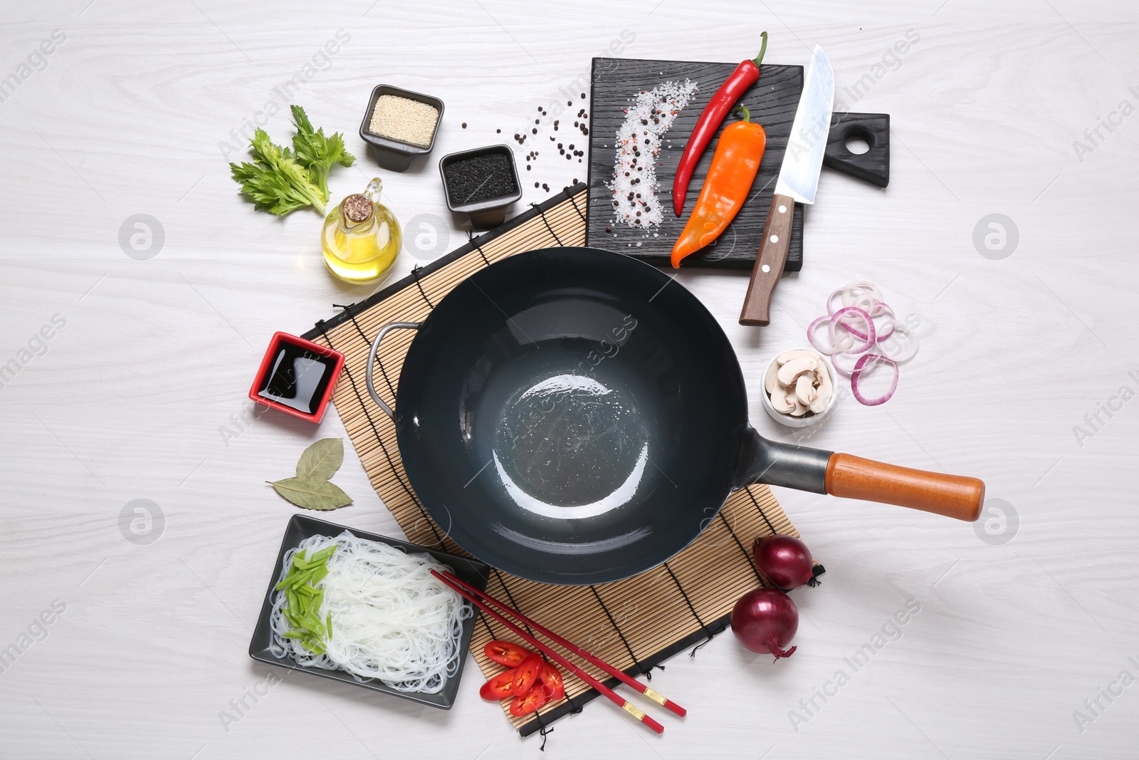 Photo of Wok, chopsticks and different products on white wooden table, flat lay