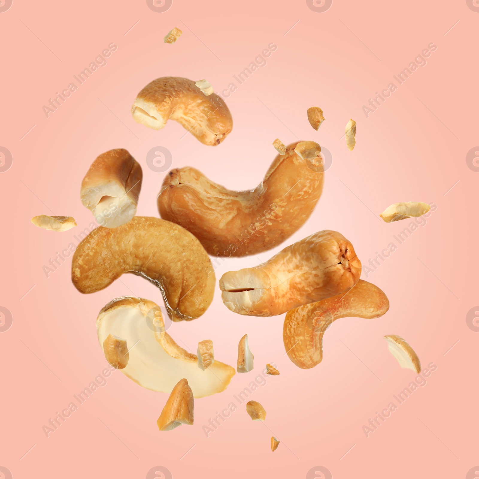 Image of Tasty cashew nuts flying on pink background