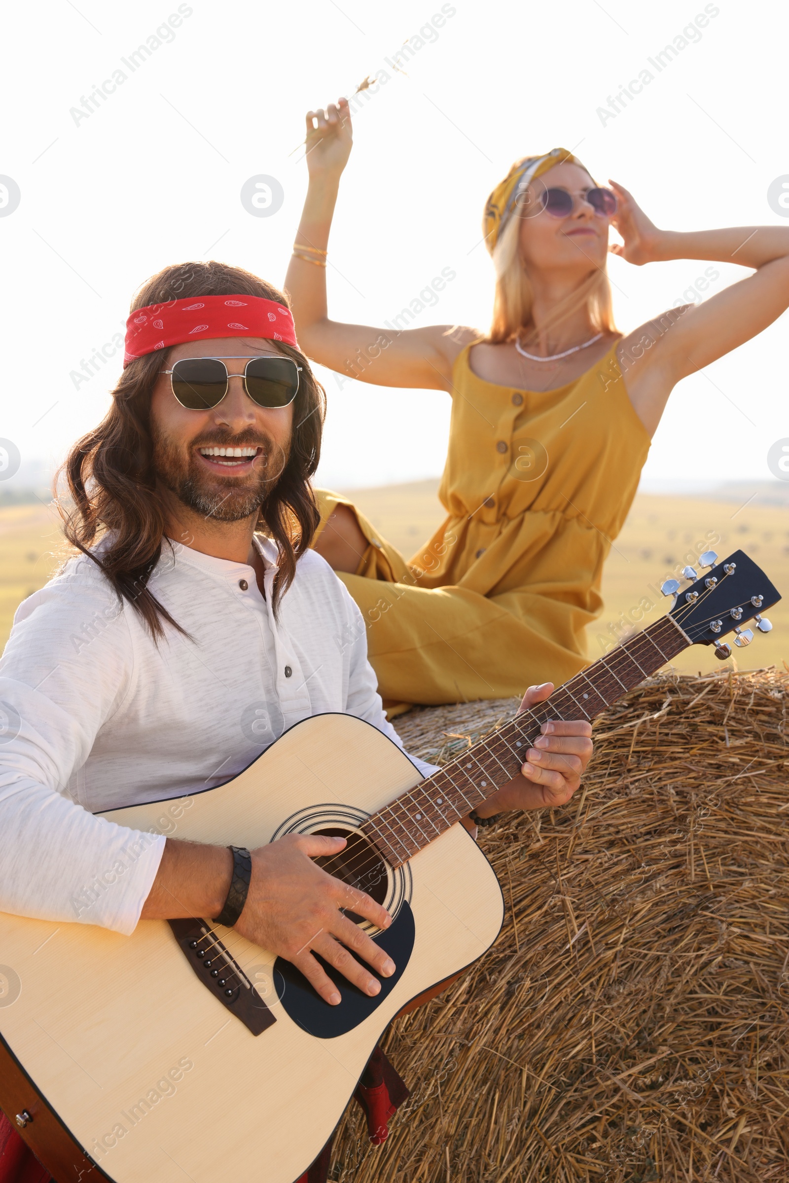 Photo of Beautiful hippie woman listening to her friend playing guitar in field