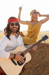 Photo of Beautiful hippie woman listening to her friend playing guitar in field