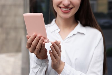 Young woman looking at herself in cosmetic pocket mirror outdoors, closeup