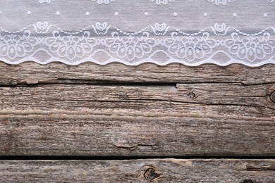 White lace on wooden table, top view. Space for text