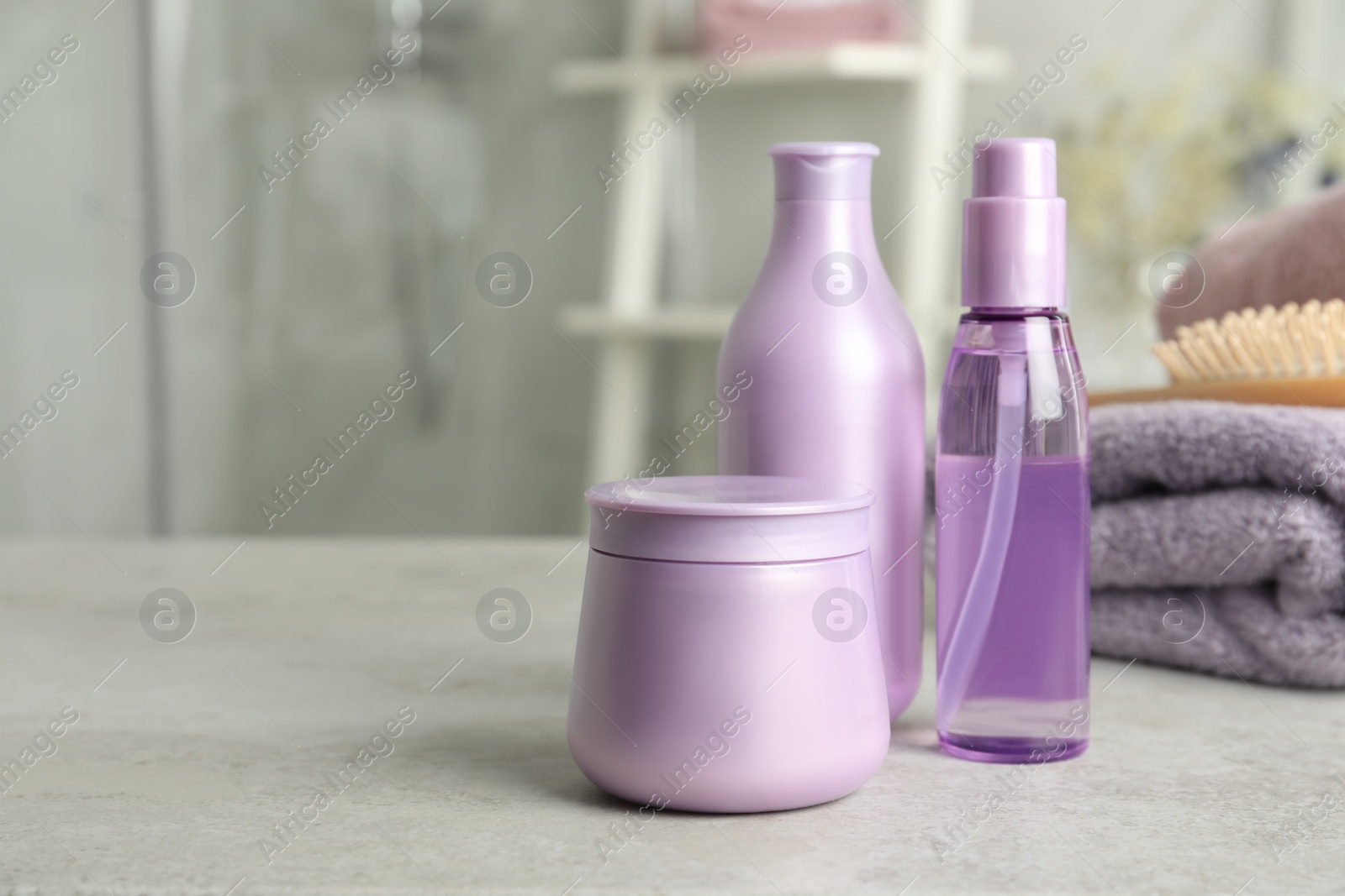 Photo of Set of hair care cosmetic products on light grey stone table in bathroom. Space for text