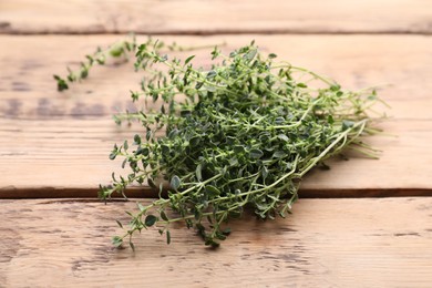 Photo of Bunch of aromatic thyme on wooden table, closeup. Fresh herb