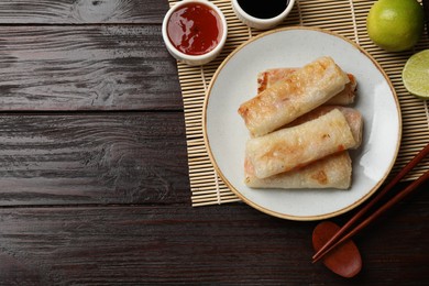 Photo of Delicious fried spring rolls served on wooden table, flat lay. Space for text