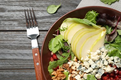 Photo of Tasty salad with pear slices served on black wooden table, flat lay