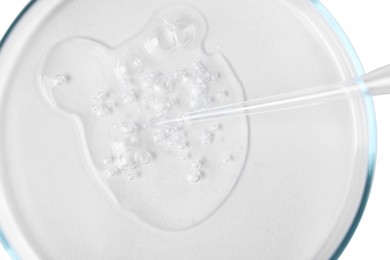 Photo of Glass pipette and petri dish with liquid on white background, top view