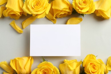 Photo of Beautiful yellow roses and blank card on light grey background, flat lay. Space for text