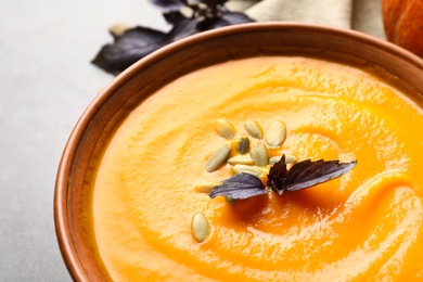 Photo of Bowl with tasty pumpkin soup on gray table, closeup